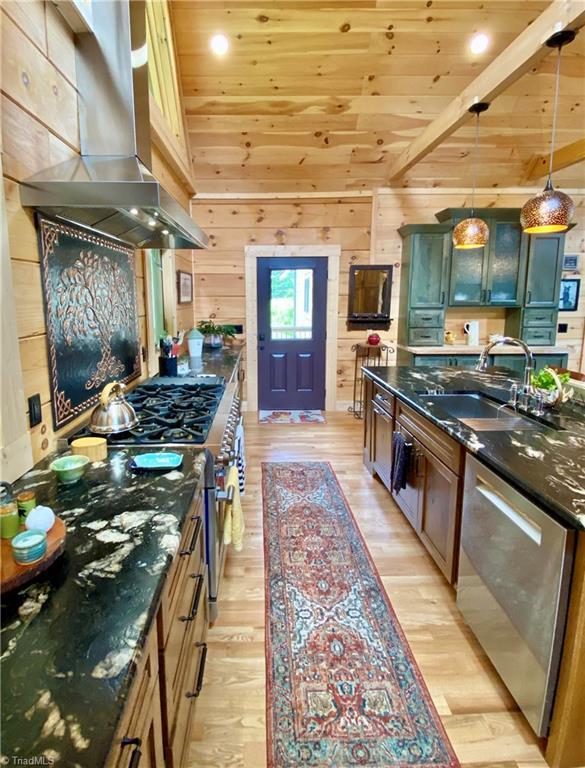 1295 Will Vannoy Rd, West Jefferson, NC 28694 - kitchen with ventilation hood, stainless steel appliances, wooden ceiling, light wood-style floors, and wooden walls