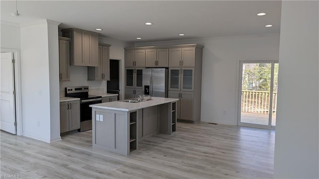 kitchen featuring ornamental molding, appliances with stainless steel finishes, gray cabinets, and an island with sink