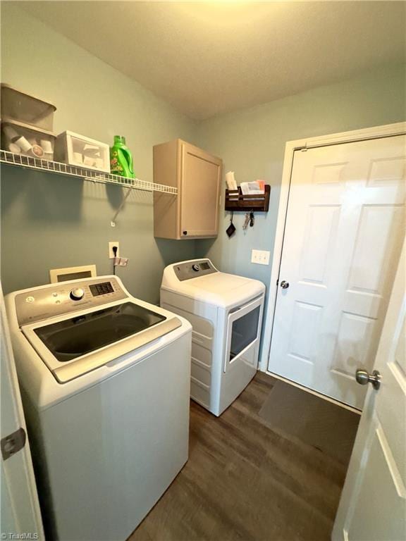 washroom featuring independent washer and dryer, dark wood finished floors, and cabinet space