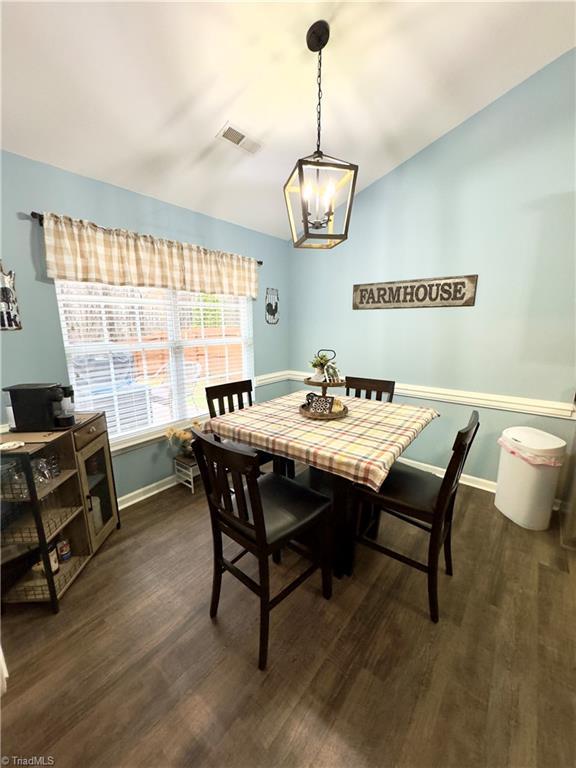 dining area featuring lofted ceiling, dark wood-style flooring, visible vents, and baseboards