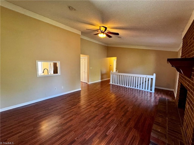 unfurnished living room featuring a brick fireplace, ceiling fan, dark wood-type flooring, and a textured ceiling