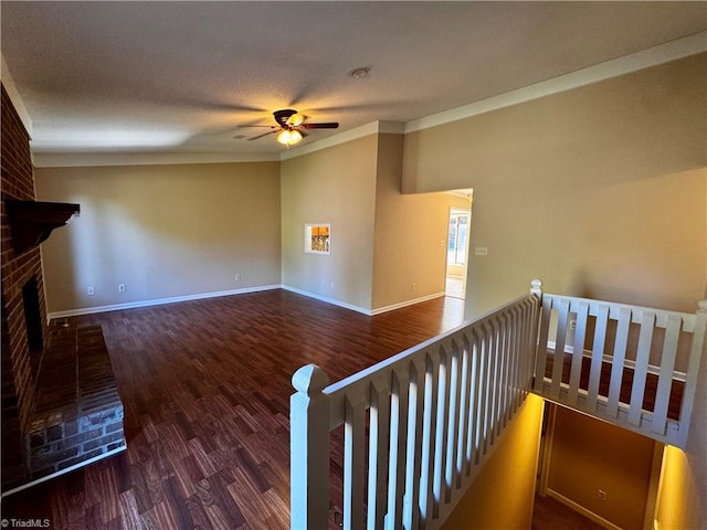 unfurnished living room with ornamental molding, a brick fireplace, ceiling fan, and dark hardwood / wood-style flooring