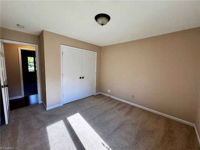 unfurnished bedroom with a closet and dark carpet