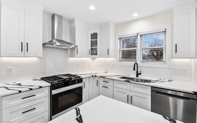 kitchen featuring white cabinetry, dishwasher, gas stove, and wall chimney exhaust hood