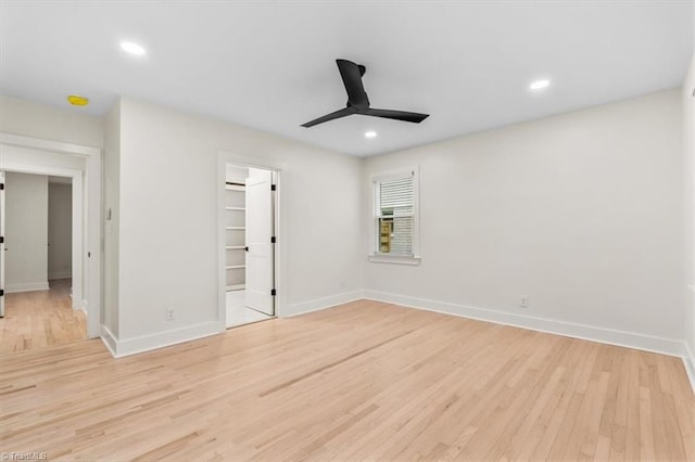 unfurnished bedroom featuring a closet, a walk in closet, ceiling fan, and light hardwood / wood-style floors