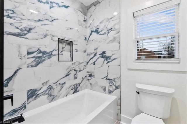 bathroom featuring tiled shower / bath combo and toilet