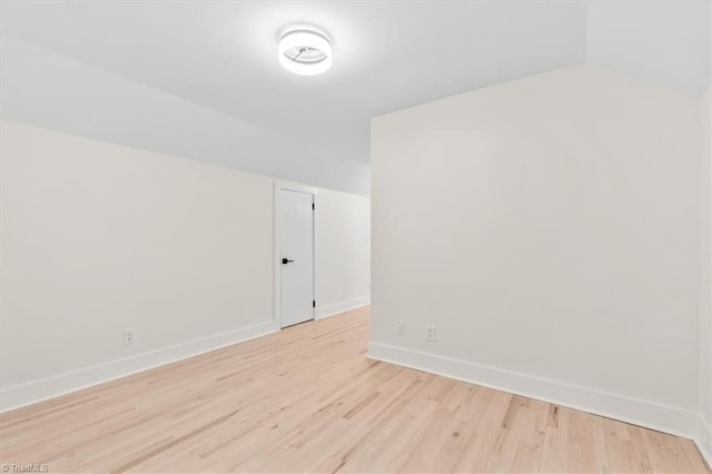 spare room with lofted ceiling and light wood-type flooring