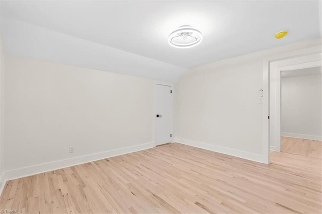 unfurnished room with light hardwood / wood-style floors and vaulted ceiling