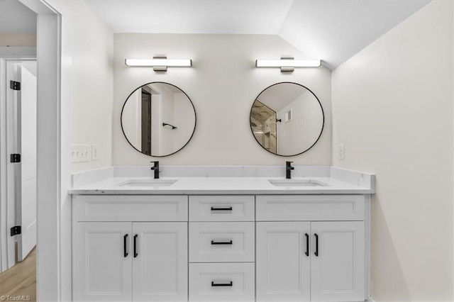 bathroom with hardwood / wood-style floors, vaulted ceiling, and vanity