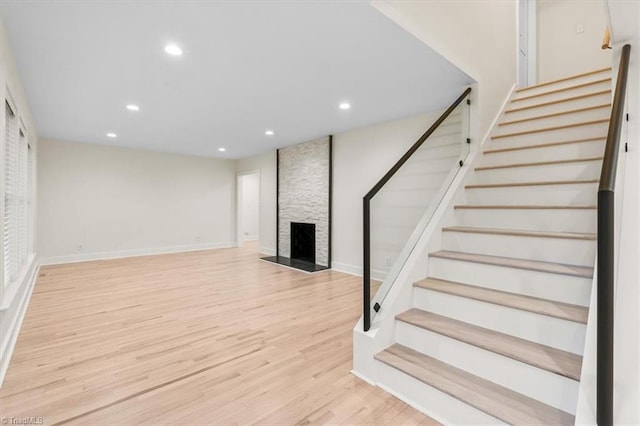 basement featuring light hardwood / wood-style flooring and a stone fireplace