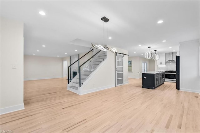 unfurnished living room featuring a barn door and light hardwood / wood-style flooring