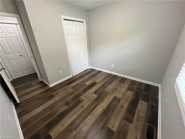 unfurnished bedroom with dark wood-type flooring