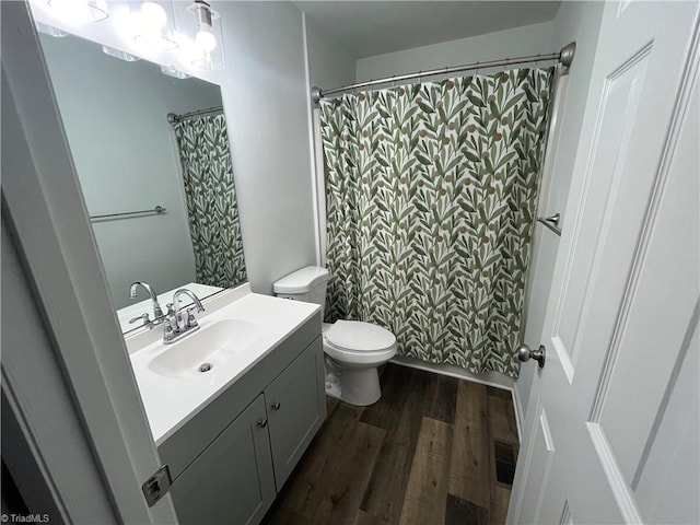 bathroom with walk in shower, hardwood / wood-style floors, vanity, and toilet