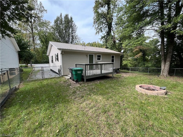 rear view of property with a lawn, a deck, and an outdoor fire pit