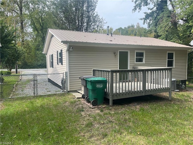 rear view of property featuring a wooden deck and a lawn