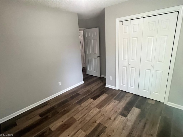 unfurnished bedroom with a textured ceiling, a closet, and dark hardwood / wood-style flooring