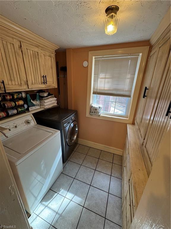 209 Abernathy St NW, Lenoir, NC 28645 - laundry room with washer and clothes dryer, cabinet space, baseboards, light tile patterned floors, and a textured ceiling