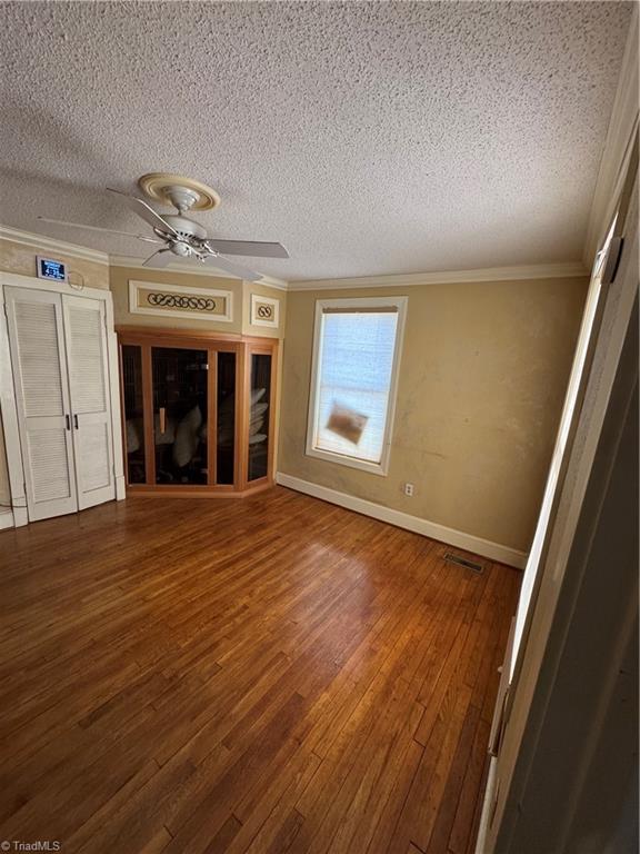 209 Abernathy St NW, Lenoir, NC 28645 - unfurnished living room with crown molding, a textured ceiling, wood-type flooring, baseboards, and ceiling fan