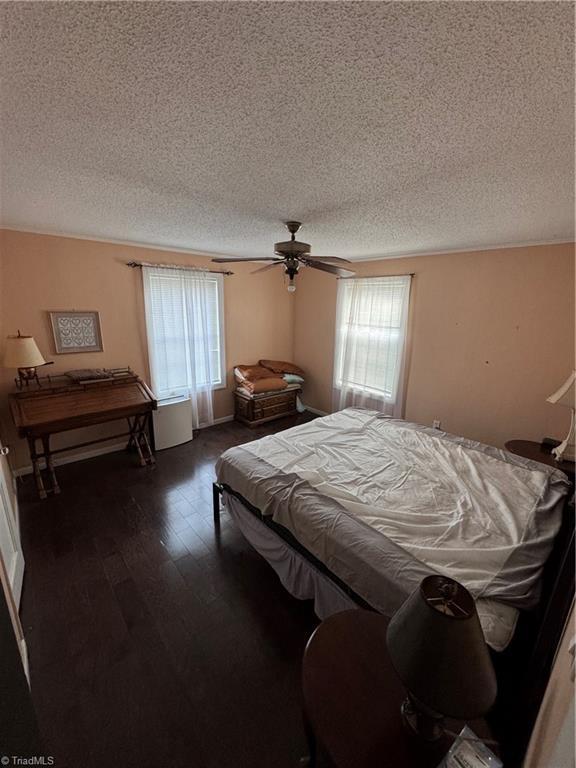 209 Abernathy St NW, Lenoir, NC 28645 - bedroom with multiple windows, a textured ceiling, dark wood-style flooring, and a ceiling fan