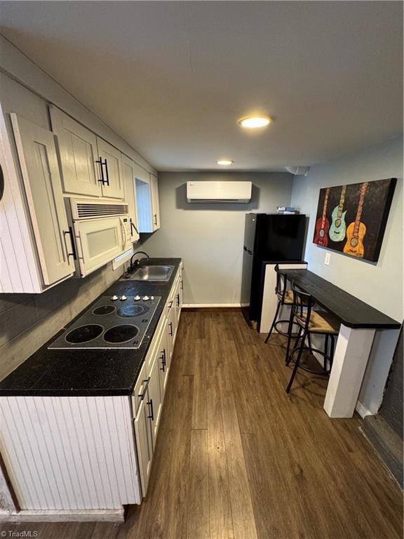 209 Abernathy St NW, Lenoir, NC 28645 - kitchen with white microwave, a wall mounted AC, dark wood-style flooring, freestanding refrigerator, and electric cooktop