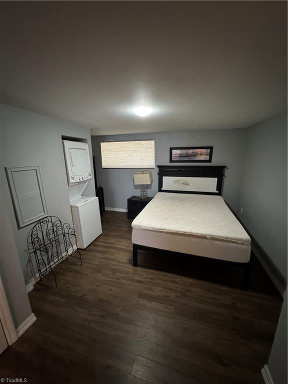 209 Abernathy St NW, Lenoir, NC 28645 - bedroom featuring stacked washing machine and dryer, dark wood-style flooring, and baseboards