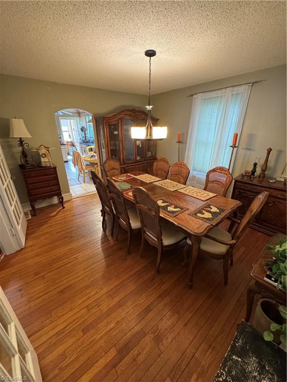 209 Abernathy St NW, Lenoir, NC 28645 - dining room with light wood-style floors, a textured ceiling, and arched walkways