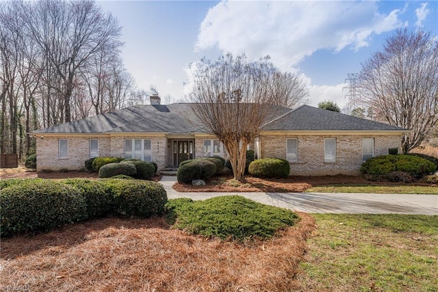 single story home featuring brick siding and a chimney