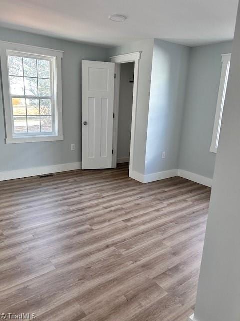 empty room featuring visible vents, light wood-style flooring, and baseboards