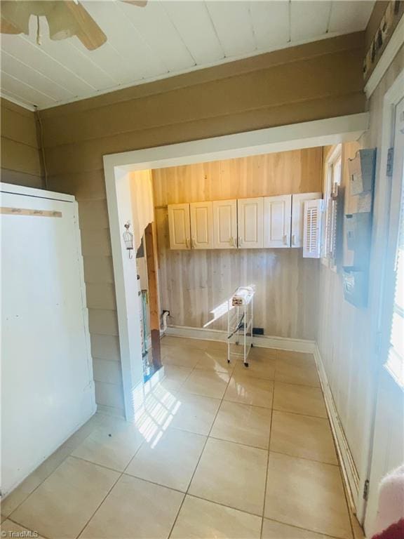 hallway featuring wooden walls and light tile patterned flooring