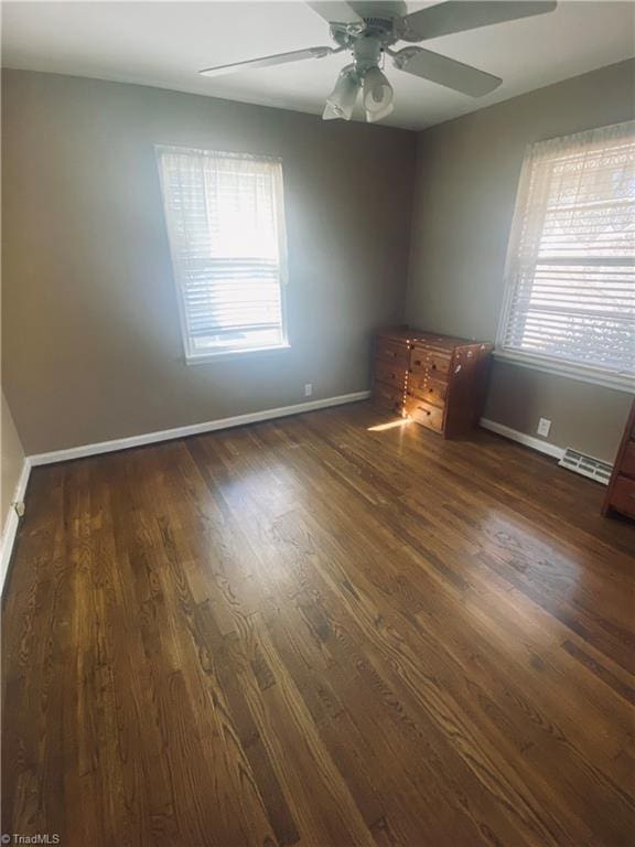 empty room with ceiling fan and dark hardwood / wood-style flooring