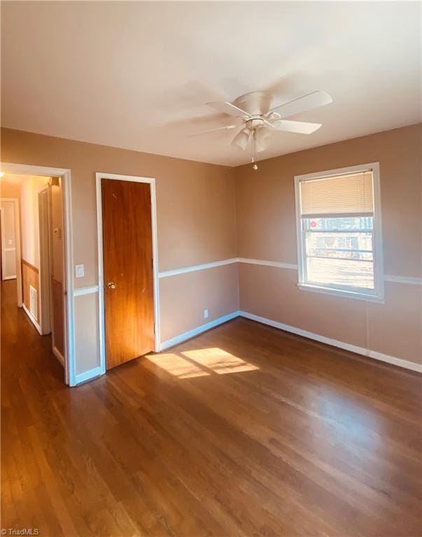 unfurnished room with ceiling fan and dark wood-type flooring