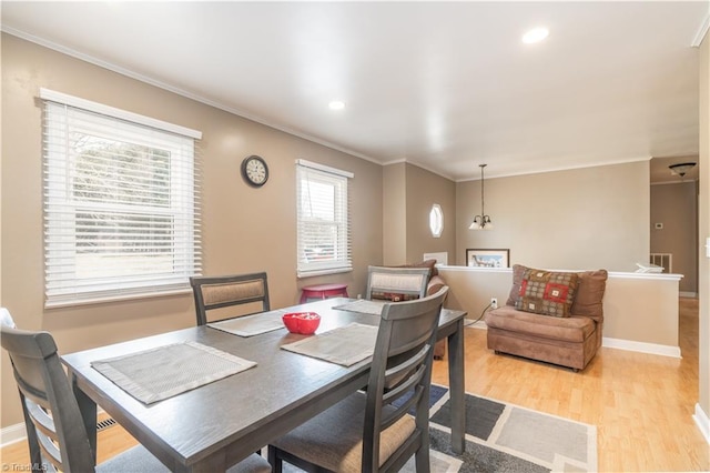 dining area featuring ornamental molding and light hardwood / wood-style floors