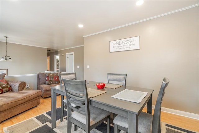 dining area with ornamental molding, an inviting chandelier, and light hardwood / wood-style flooring