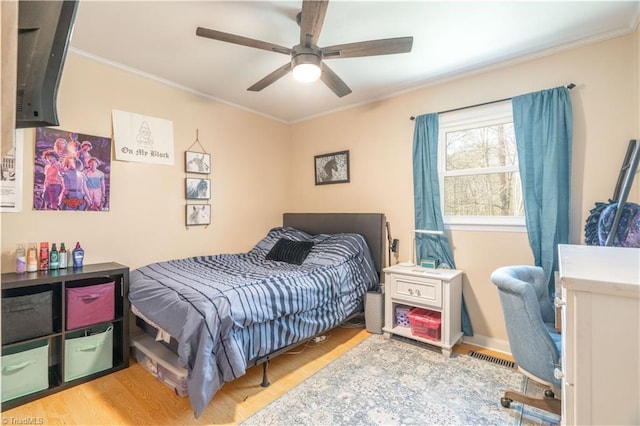 bedroom with crown molding, ceiling fan, and light hardwood / wood-style flooring