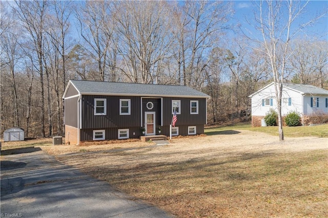 raised ranch featuring a front lawn and central air condition unit