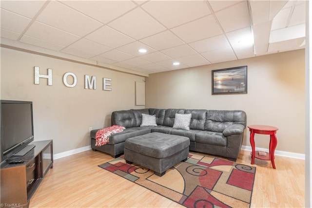 living room with a drop ceiling and light wood-type flooring