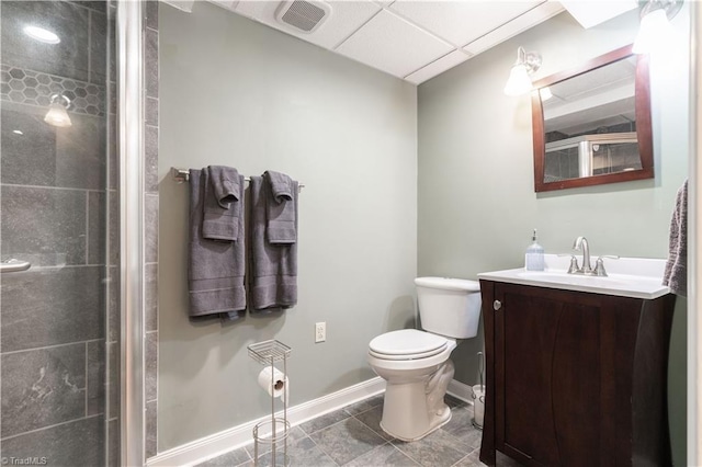 bathroom featuring a paneled ceiling, vanity, tile patterned floors, toilet, and walk in shower