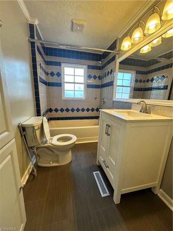 full bathroom featuring toilet, crown molding, a textured ceiling, vanity, and tiled shower / bath combo