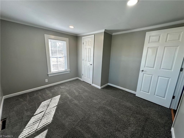 unfurnished bedroom featuring dark colored carpet, crown molding, and a closet