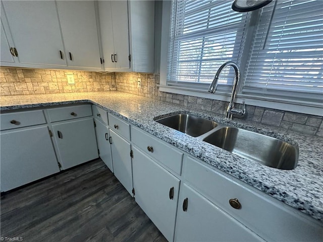 kitchen with sink, white cabinetry, backsplash, light stone counters, and dark hardwood / wood-style flooring