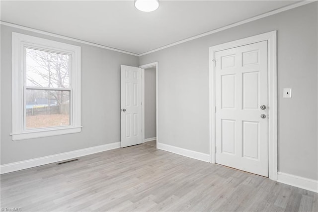 unfurnished bedroom featuring visible vents, baseboards, light wood-type flooring, and ornamental molding