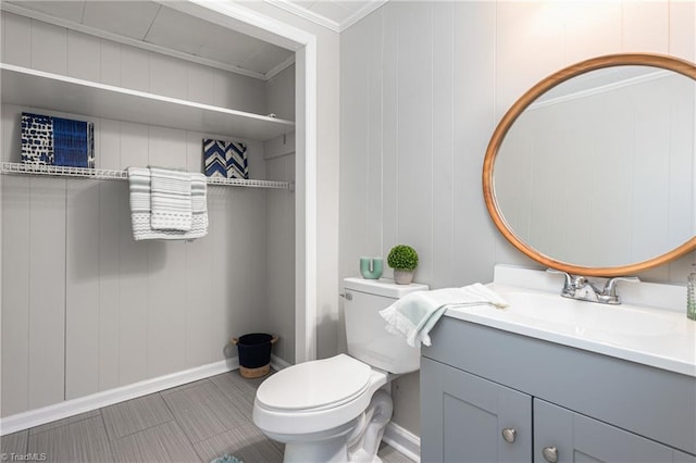 bathroom with baseboards, toilet, ornamental molding, and vanity