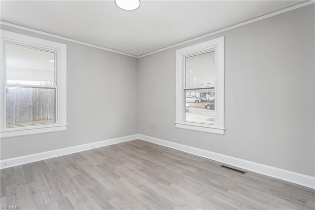 unfurnished room with visible vents, baseboards, wood finished floors, and ornamental molding