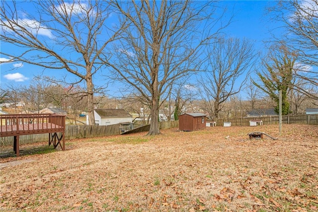 view of yard with an outdoor structure, a fenced backyard, a shed, and a wooden deck