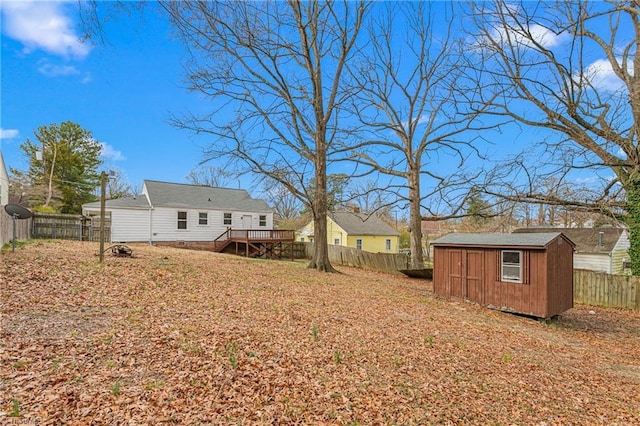 view of yard with a wooden deck, an outbuilding, a fenced backyard, and a shed