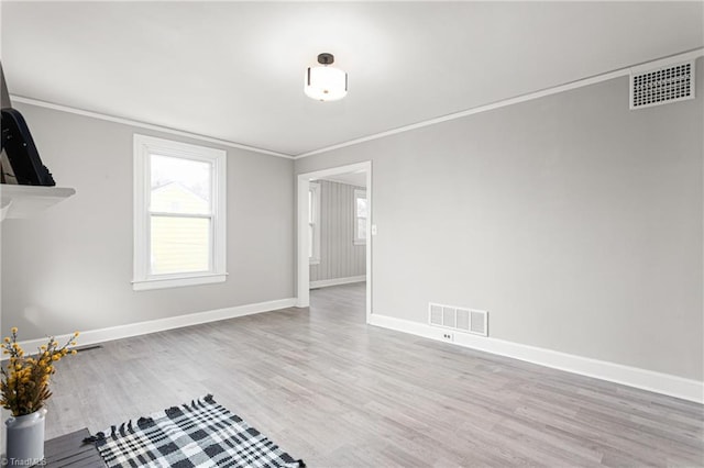 empty room featuring wood finished floors, baseboards, visible vents, and ornamental molding