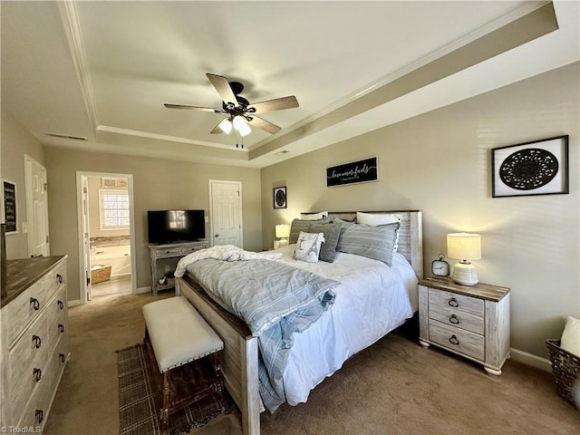 carpeted bedroom featuring a tray ceiling, ceiling fan, crown molding, and ensuite bathroom