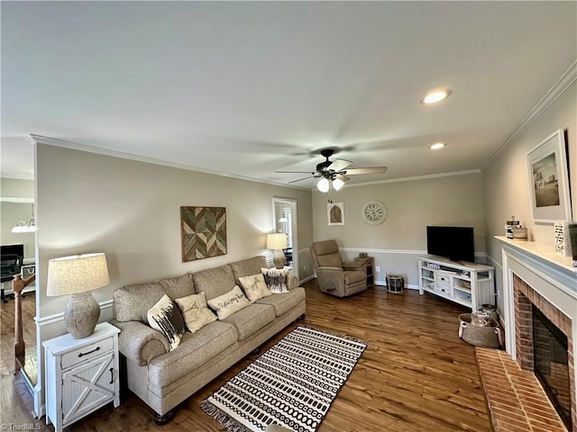 living room with a brick fireplace, ceiling fan, dark hardwood / wood-style flooring, and ornamental molding