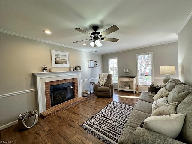 living room featuring wood-type flooring, a brick fireplace, ceiling fan, and ornamental molding