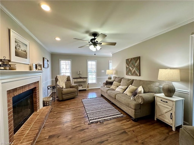 living room with crown molding, ceiling fan, dark hardwood / wood-style floors, and a brick fireplace